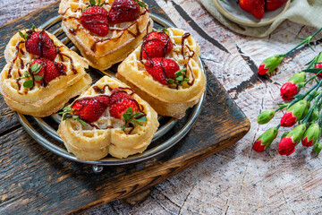 Heart-shaped belgian waffles decorated with fresh strawberries