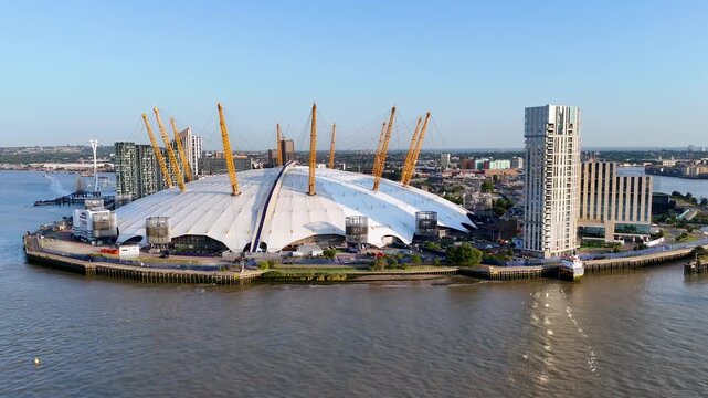 Slow aerial drone flight over the  Arena and River Thames at golden hour. Modern London skyline blending architecture, light, and calm cinematic movement.