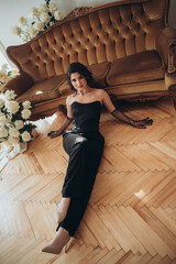 Woman in black dress lying gracefully on wooden floor