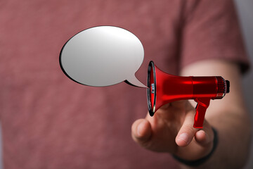 Image of a hand holding a red megaphone with a blank speech bubble, symbolizing communication,...