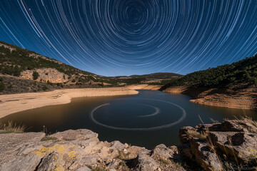 A celestial vortex of star trails reflected on a mountain reservoir  