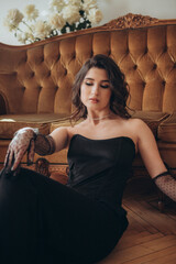 Graceful woman in black dress relaxing by sofa