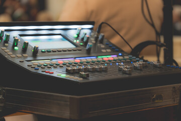 Sound engineer adjusting audio mixing console with colorful lights and controls in studio or live concert setup