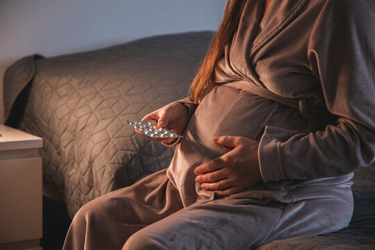 Pregnant young woman taking pills or vitamins