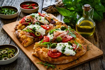 Fototapete Rund Pizzeria Pinsa with cured ham, burrata cheese, tomatoes, green olives and arugula on wooden table   © Jacek Chabraszewski