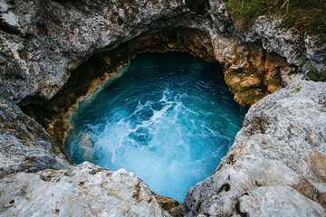 A crystal-blue karst spring bubbling up from a rocky outcrop