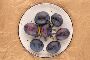 Sweet plums on kraft paper, close-up, top view.