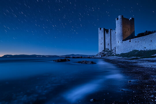 A castle standing on the shore of a sea that glows every night  