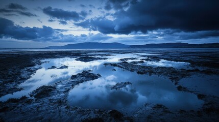 Rippling lake water reflecting mountains under dramatic clouds