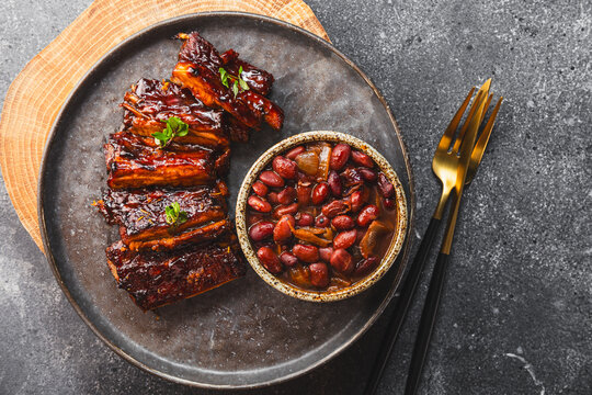 Sliced grilled meat steak Rib eye medium rare set, in a black plate, with beans, on grey background top view