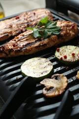 Electric grill with tasty chicken fillet, mushrooms, spices and zucchini, closeup