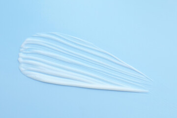 Sample of moisturizing cream on light blue background, top view