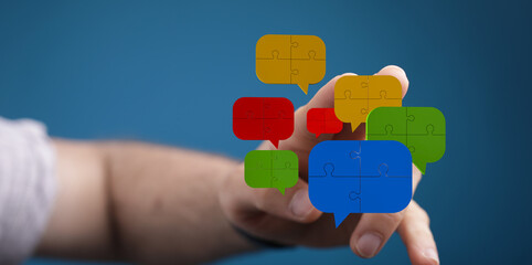 Hand holding colorful dialogue bubble puzzle pieces symbolizing communication, connection,...