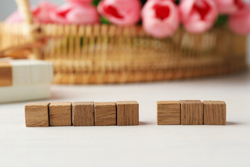 Blank wooden cubes and flowers on white table, selective focus. Mockup for design