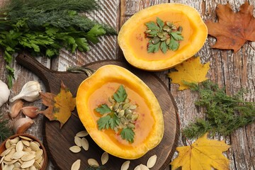 Tasty pumpkin cream soup with seeds, parsley, dill and autumn leaves on color wooden table, flat lay