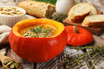 Tasty pumpkin cream soup with seeds, dill and thyme on color wooden table, closeup