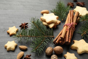 Christmas composition with fir tree branches, cookies and spices on black table, closeup