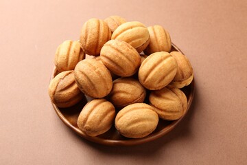 Delicious nut shaped cookies with boiled condensed milk on brown background, closeup