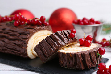 Delicious Yule log (traditional Christmas cake) with redcurrant on table, closeup