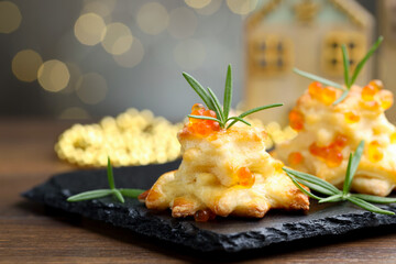 Tasty snacks with puff pastry, red caviar and rosemary on wooden table against grey background with...