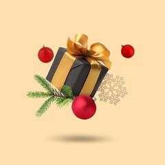 Christmas or New Year celebration. Gift box and festive decor flying on beige background