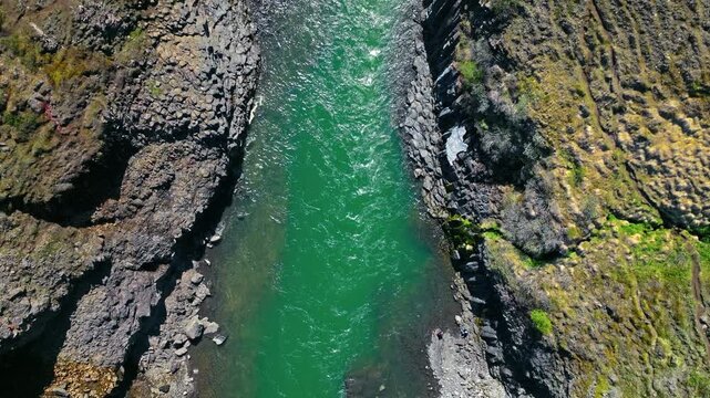 Top-down drone view of Stu&eth;lagil Canyon in East Iceland. The turquoise river carves a winding path between steep basalt cliffs.