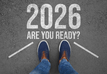 New 2026 Year. Man standing in front of phrase Are You Ready? and numbers on asphalt, top view