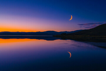 A glowing crescent lake reflecting the rising moon  