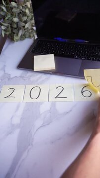 Hand changing sticky notes from 2025 to 2026