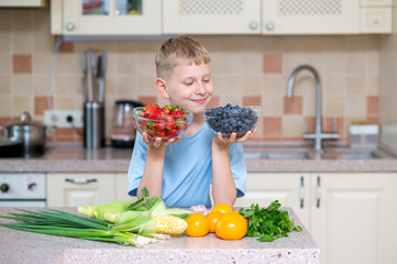 Boy holding bowls of strawberries and blueberries in kitchen