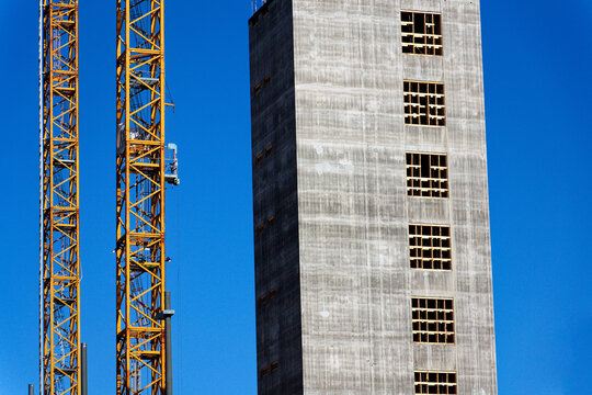 Two yellow cranes on skyscraper construction site of timber building Kaj 16 with hybrid concrete frames, sunny day, Lilla Bommen area, Gothenburg, Sweden