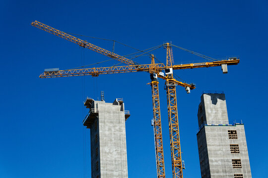 Yellow cranes on construction site of timber building Kaj 16 with hybrid concrete frames, sunny day, Lilla Bommen area on May 12, 2025 in Gothenburg, Sweden.