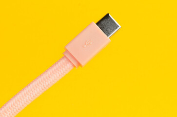 Close-up of a pink USB-C charging cable on a vibrant yellow background