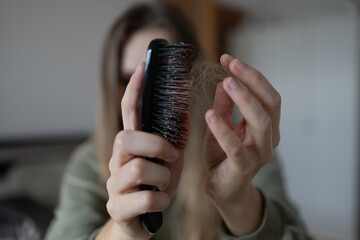 Healthy concept. woman shows comb with long fallen hair.