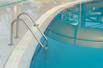 Hotel Pool With Stainless Ladder And Curved Glass Reflections Over Bright Water