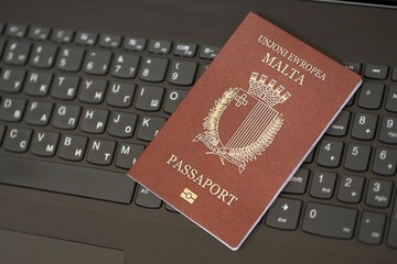 Malta passport lies on black laptop keyboard buttons background close up. Technologies and control in Europe concept