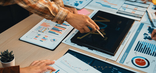 A collaborative business meeting featuring hands analyzing financial data on documents and charts. Emphasis on teamwork and strategic decision-making in a professional setting. SACTR