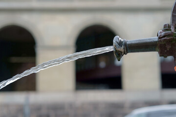 Clean water flowing from the old drinking fountain, selective focus