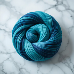 A beautifully wound ball of blue and aqua gradient yarn resting on a cool marble surface.