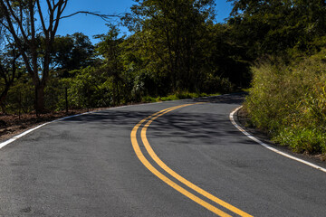 Fototapeta premium View of an empty paved rural road, flanked by Atlantic forest and eucalyptus fields in a mountain range in Brazil