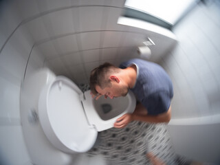 Hungover man feeling sick by the toilet after a night of heavy drinking