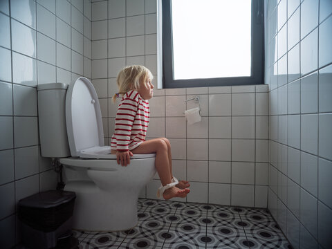 Little 4 year old girl sitting on the toilet during potty training at home