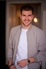 Portrait of a young man standing indoor and smiling at camera