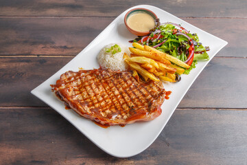 Côte de veau grillée avec frites, salade et sauce — plat traditionnel de brasserie française, servie sur une table en bois.