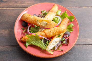 Börek turc servi dans une assiette colorée sur table en bois – présentation moderne. Variété de pâtisserie salée. 
