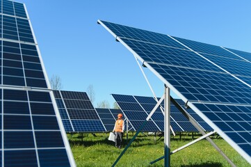 Worker walking in solar panel farm carrying equipment