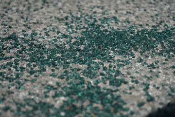 Fragments of broken glass sparkling on rough pavement.