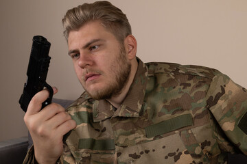 A soldier in camouflage uniform is intently inspecting a handgun