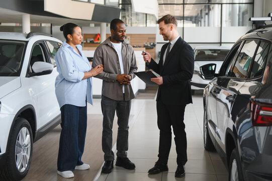 African american couple consulting with car salesman