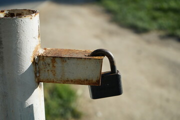Close-up of a weathered padlock on rusty metal latch